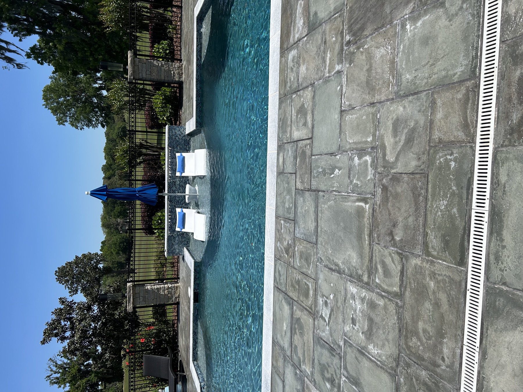 Finished Koah pool with a water wall, sun shelf loungers, and golf-course view