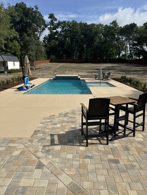Finished Koah pool with paver patio, sun shelf, spa, and outdoor seating