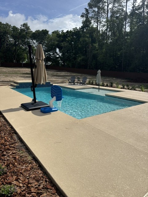 Finished Koah pool with shallow shelf, umbrella, and clear water